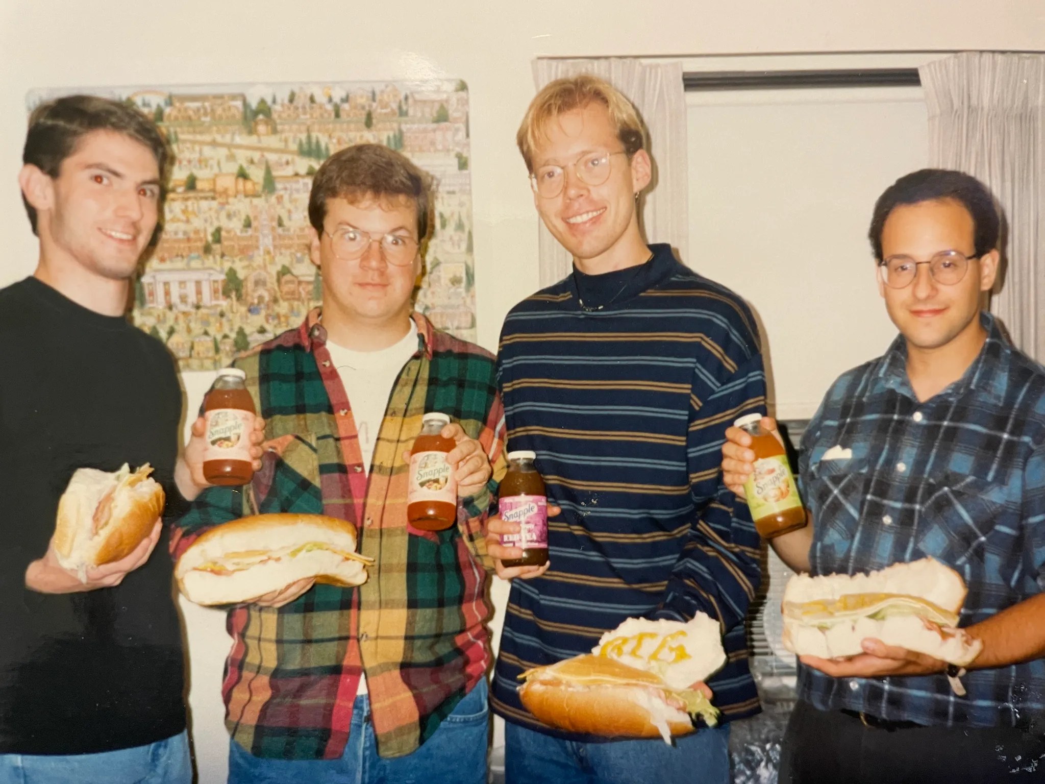 Four BIG Sandwich Night founders holding up loaf-sized sandwiches and Snapple bottles, Grinnell College, 1994